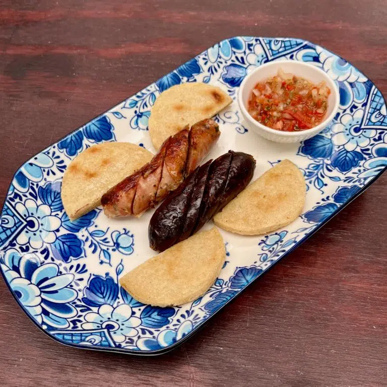 Matrimonio Colombo Argentino 1 morcilla artesanal Colombiana + 1 chorizo artesanal Argentino. Acompañados por arepa de máiz blanco y salsa criolla.